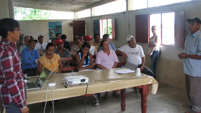 Taller comunitario con participantes reunidos alrededor de mesas.