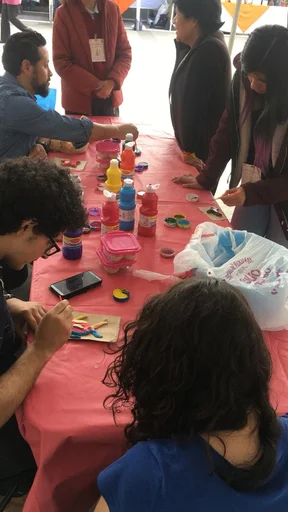 Personas participan en una actividad práctica de divulgación alrededor de una mesa.